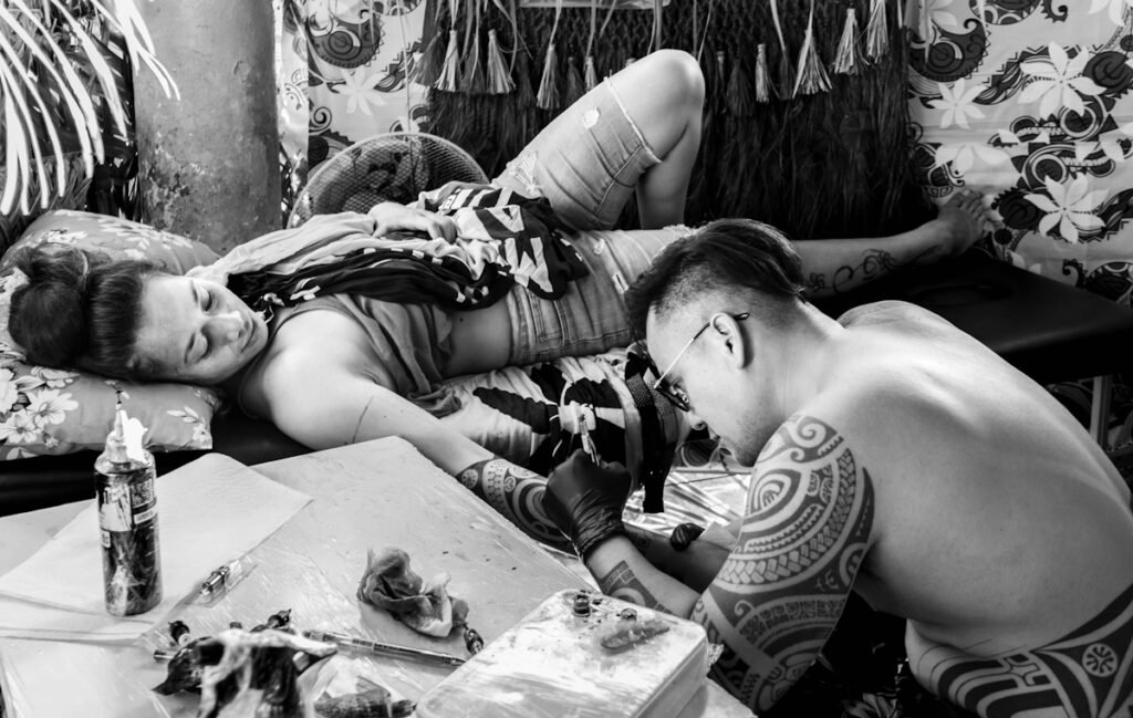 kaipeka tattoo en train de tatouer une jeune femme au bras pendant la convention de tatouage