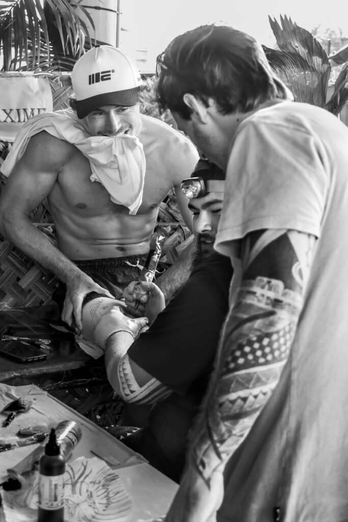 un homme en train de se faire tatouer la jambe par maxime heyraud pendant une convention de tatouage en polynésie française