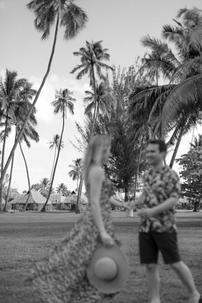 photo noir et blanc d'un jeune couple de mariés qui danse dans un parc à moorea avec les palmiers en fond