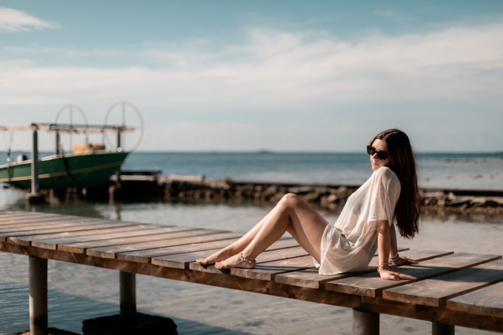 jeune femme assise sur un ponton au bord de l'eau à la pension la perle de taha'a en polynésie française en lumière naturelle