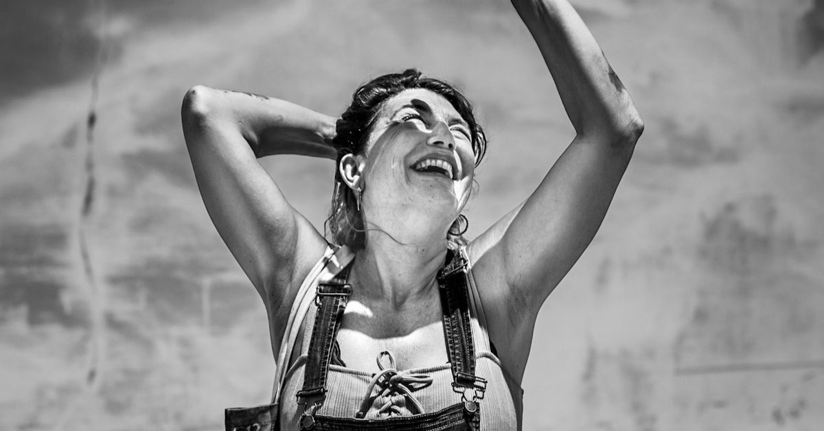 photo noir et blanc de marie une femme habillée avec une salopette qui sourit photo réalisée à raiatea en polynésie française prise par la photographe marie production basée à rennes en bretagne