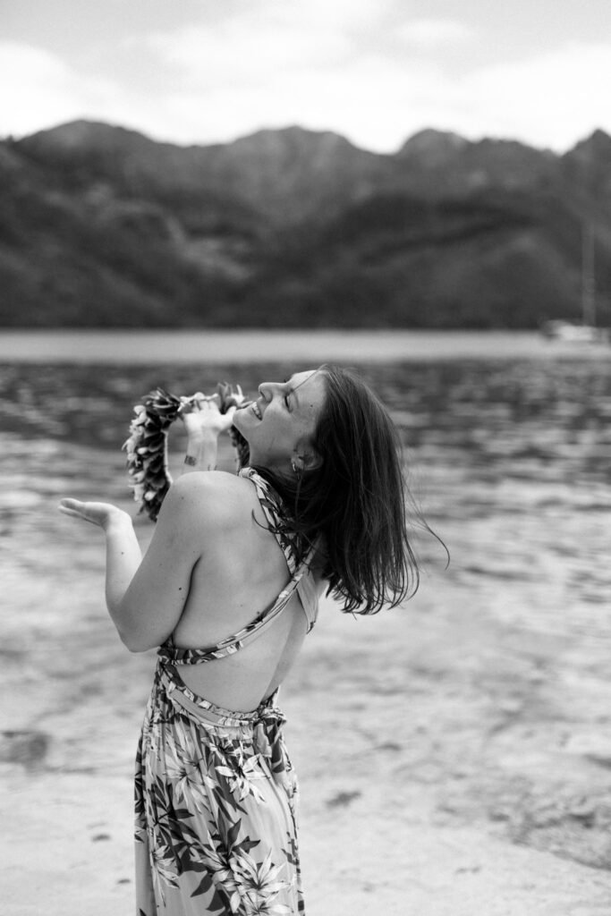 femme heureuse en noir et blanc au bord de l'eau sur une plage à moorea en polynésie française photographe marie lallemant située à rennes en Bretagne