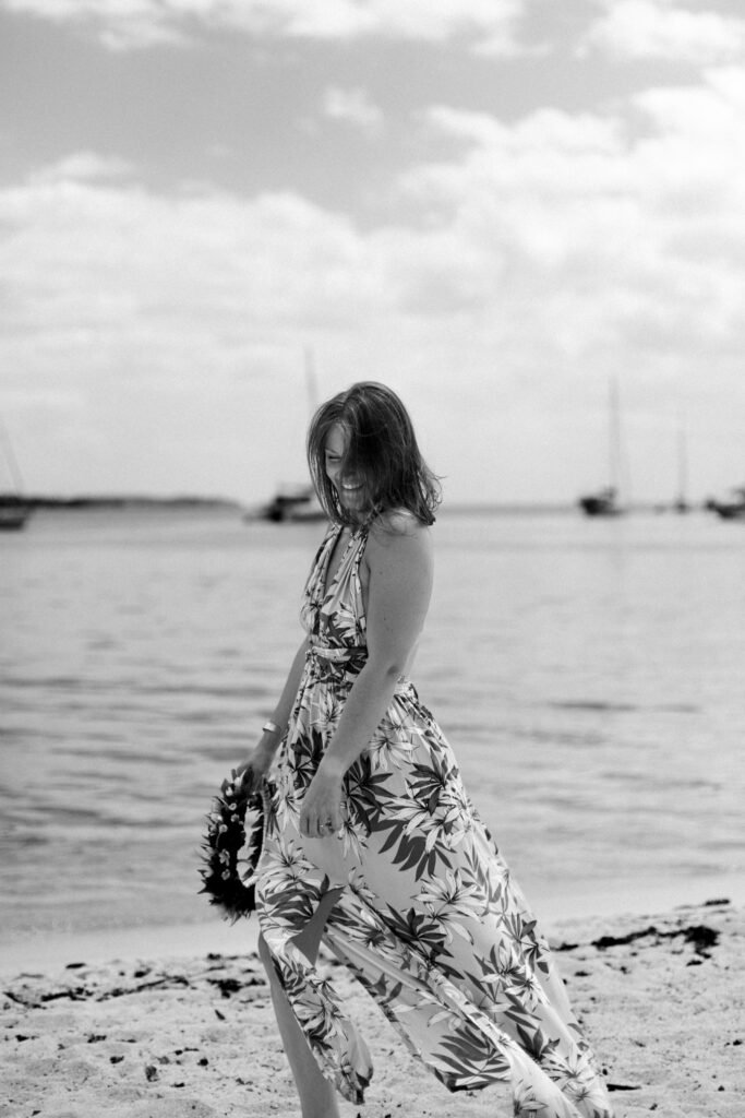 femme qui rigole en noir et blanc au bord de l'eau sur une plage à moorea en polynésie française photographe marie lallemant située à rennes en Bretagne