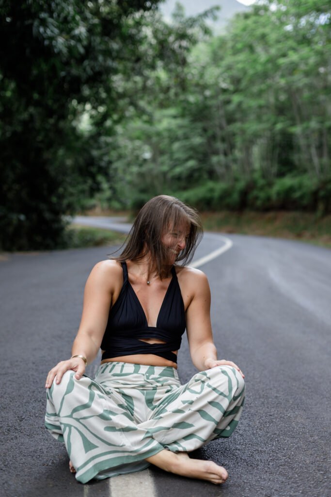 portrait d'une femme assise sur la route en tailleur en train de rire elle est heureuse photo prise par marie production photographe basée à rennes en bretagne