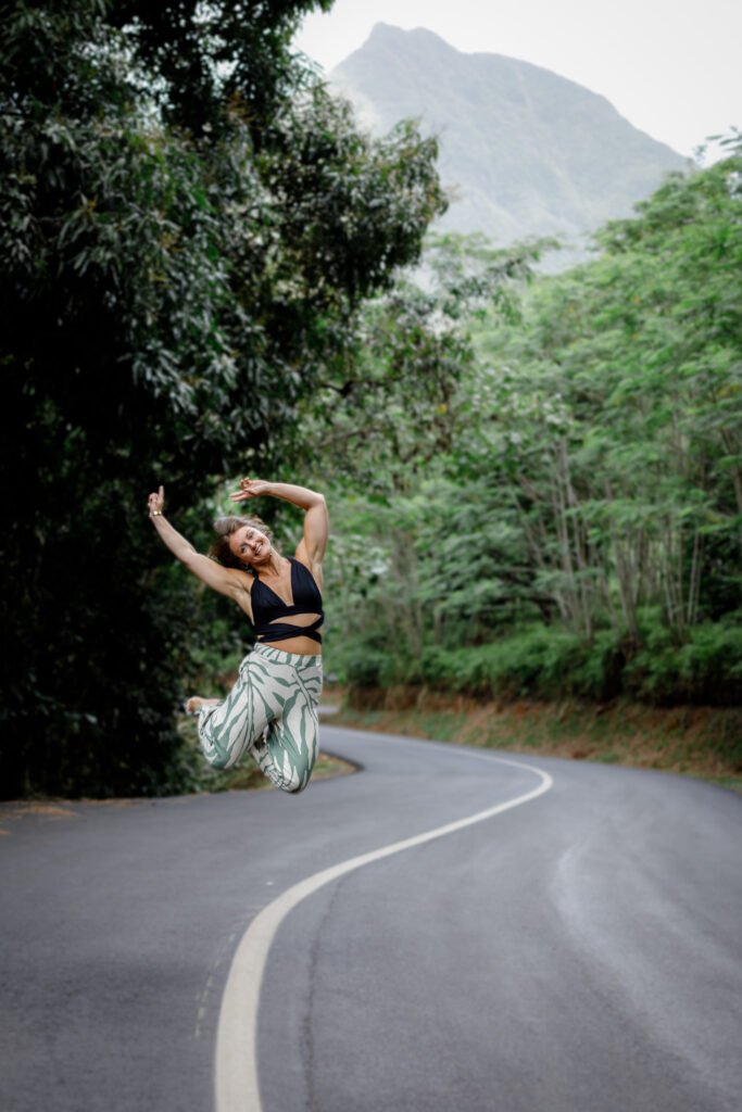 photo d'une femme qui saute au dessus d'une route entourée de végétation à moorea en polynésie française réalisée par marie production photographe à rennes en bretagne