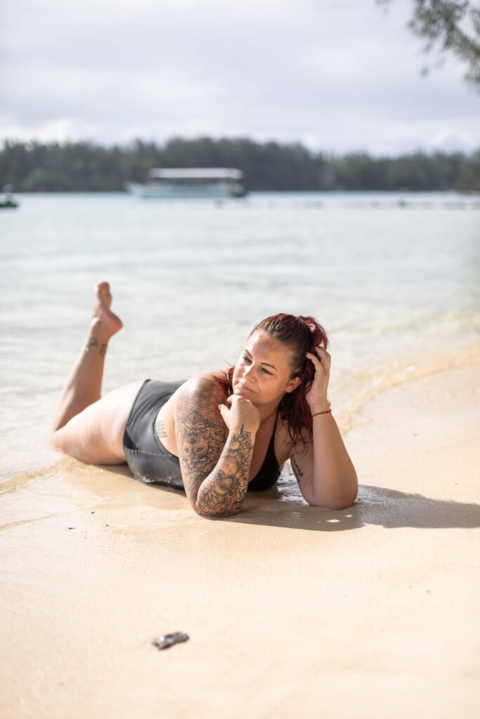 femme en maillot de bain allongée sur le ventre dans le sable sur une plage à moorea en polynésie française